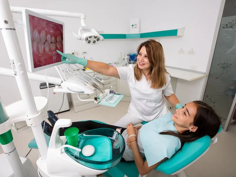 Medicul arată pe monitor imaginile dinților unei paciente așezate în fotoliul dentar